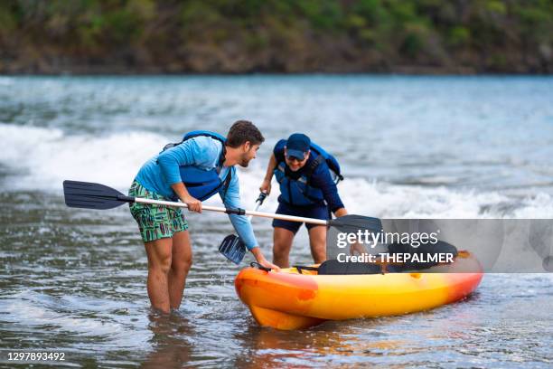 father and son pulling a kayak out of the water - carrying kayak stock pictures, royalty-free photos & images