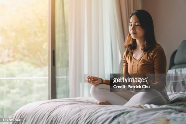 asiatica donna cinese meditando in camera da letto - vivere semplicemente foto e immagini stock