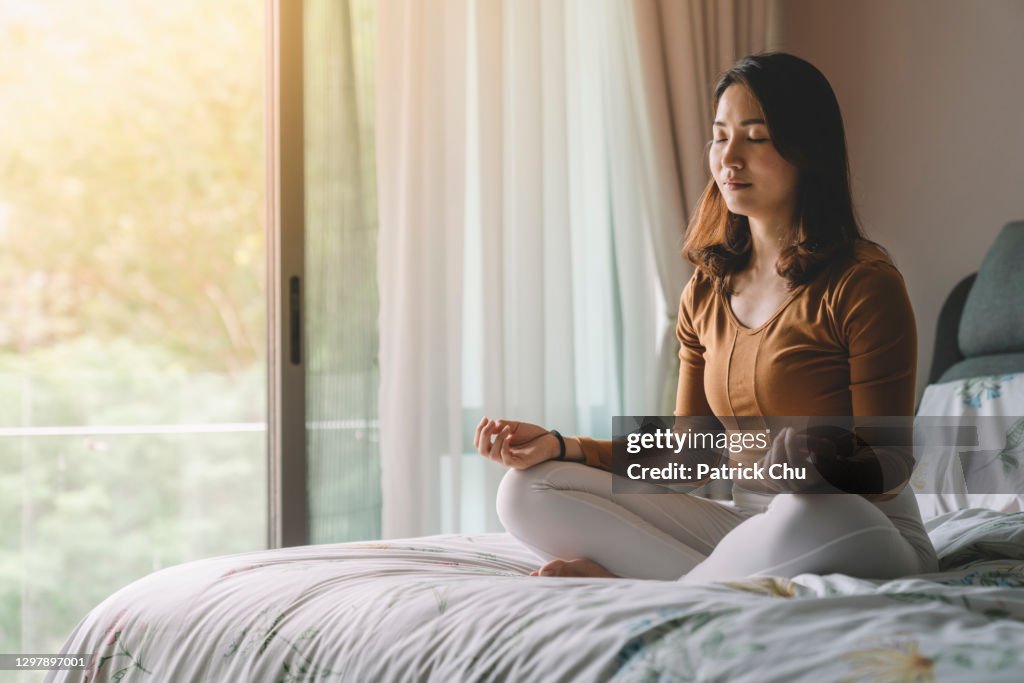Asian chinese woman meditating at bedroom