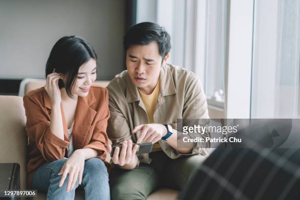 asian chinese couple using phone at apartment - couple searching the internet stock pictures, royalty-free photos & images