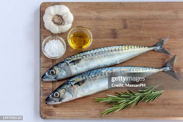 two mackerels on a board with garlic oil salt and rosemary - makreel stockfoto's en -beelden