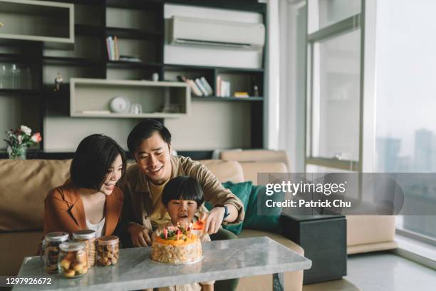 cute asian chinese child celebrating his birthday cake with their parents - young family at home stock pictures, royalty-free photos & images