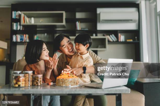 leuk aziatisch chinees kind dat zijn verjaardagscake met zijn ouders en grootouders viert gebruikend online videopraatje - chinese birthday stockfoto's en -beelden