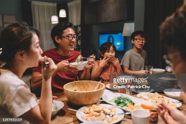 asiatische chinesische familie und cousins bei wiedersehen abendessen zu hause - warmes abendessen stock-fotos und bilder