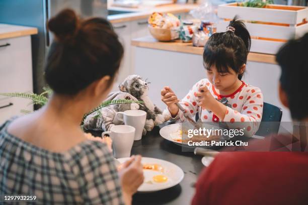 cute asian chinese girl having western breakfast with parents at kitchen - moeder kind zes melk stockfoto's en -beelden