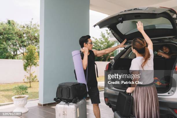 asian chinese couple unloading luggage with their daughter from their car at their house - chinese car home stockfoto's en -beelden