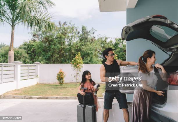 asian chinese couple unloading luggage with their daughter from their car at their house - chinese car home stockfoto's en -beelden