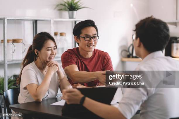 asian chinese businessman shaking hands with chinese couple in their house - asian shaking hands stockfoto's en -beelden