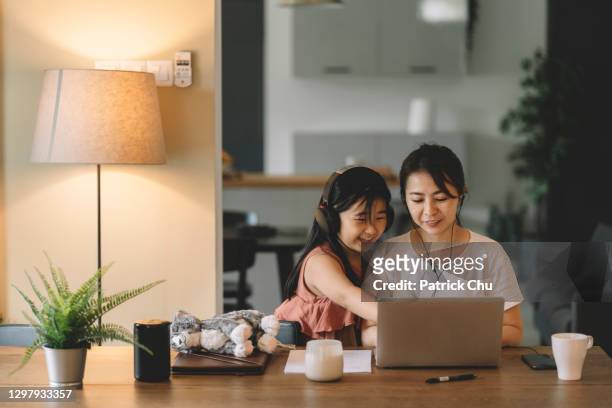 asian chinese mother and daughter using laptop browsing the internet at living room - familie online stock pictures, royalty-free photos & images