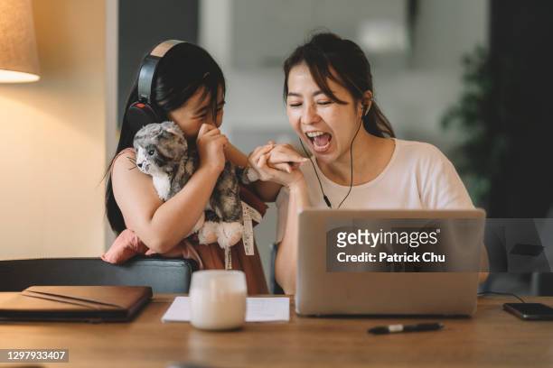 asian chinese woman working from home while having fun time with cute daughter at living room - working mother stock pictures, royalty-free photos & images
