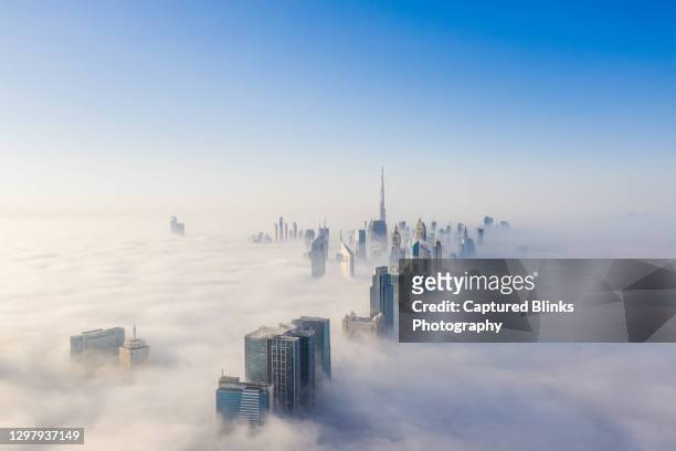 aerial view of dubai frame and skyline covered in dense fog during winter season - wolkenkratzer stock-fotos und bilder