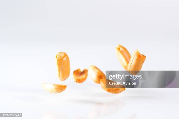 fried peanuts flying in mid air in white background - peanuts stock pictures, royalty-free photos & images