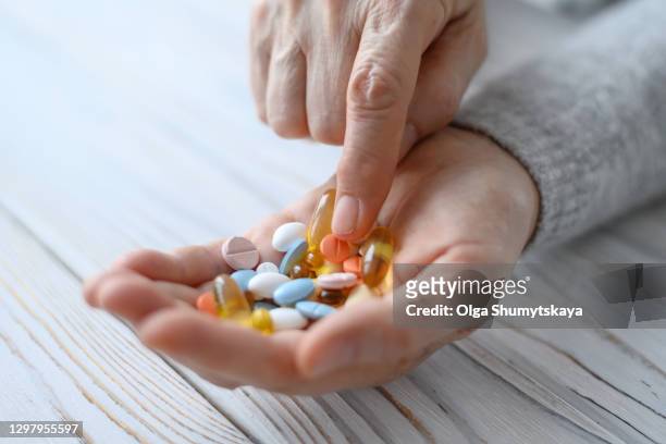 a bunch of pills in the hands of an elderly woman close-up - magnesium stock-fotos und bilder