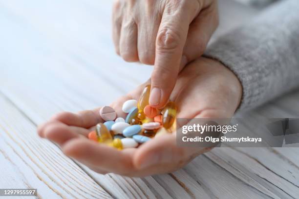a bunch of pills in the hands of an elderly woman close-up - magnesium stock pictures, royalty-free photos & images
