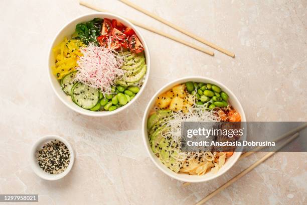 poke bowl with salmon, avocado, edamame beans, pineapple, radish and seaweed. top view. - pokes stock pictures, royalty-free photos & images