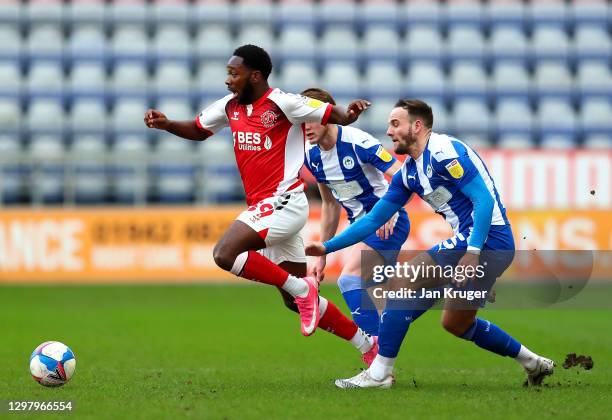 Shayden Morris of Fleetwood Town leaps over the challenge of Dan Gardner of Wigan Athletic during the Sky Bet League One match between Wigan Athletic...