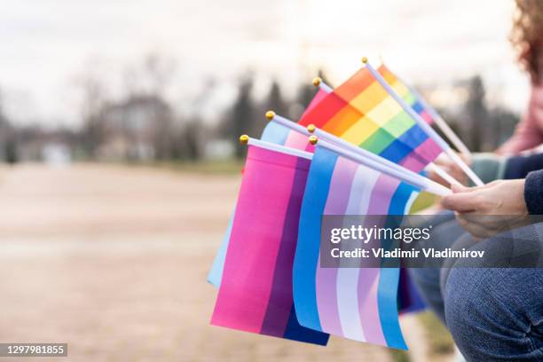 multiple pride flags hold by people - lgbtqia pride event stock pictures, royalty-free photos & images