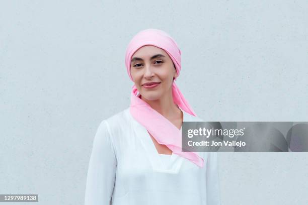 close-up of a smiling woman wearing a pink scarf in reference to cancer. - cancer survivor stockfoto's en -beelden