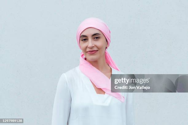 close-up of a smiling woman wearing a pink scarf in reference to cancer. - cancer portrait bildbanksfoton och bilder