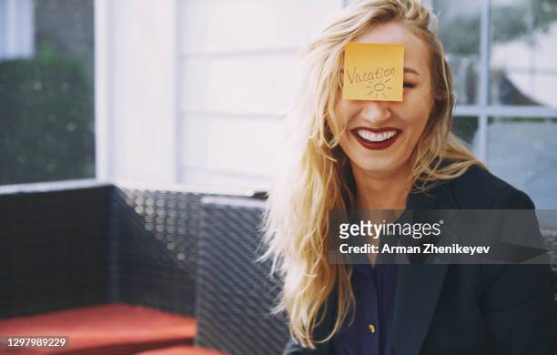 happy businesswoman with adhesive note "vacation" sticking on her forehead. - sticky stock pictures, royalty-free photos & images