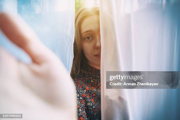 serene woman hiding behind laundry hanging on clothesline and reaching towards camera - woman reaching hands towards camera stock-fotos und bilder