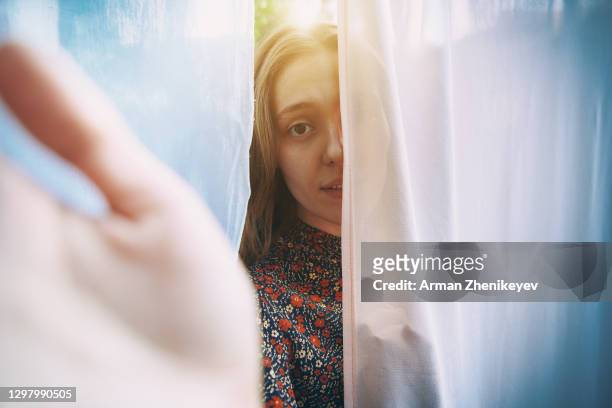 serene woman hiding behind laundry hanging on clothesline and reaching towards camera - woman reaching hands towards camera stock pictures, royalty-free photos & images
