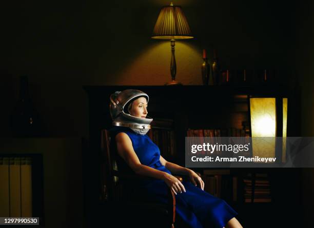 astronaut woman in a vintage dress wearing a space helmet at home. nicely fits for a book cover - cosmonaute photos et images de collection