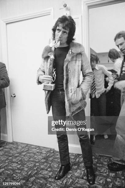 Singer Bon Scott , of rock group AC/DC, holding an award trophy backstage at the Gaumont, Southampton, during the Highway To Hell UK tour, 1979.