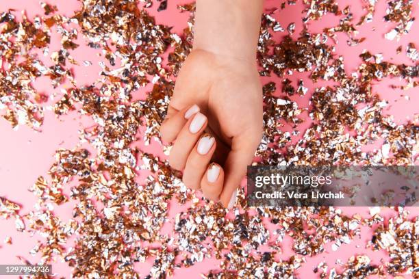 stylish pastel pink beige nails holding many multicolored sparkles - pastel colored stock-fotos und bilder