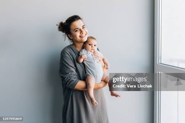 woman holding newborn baby and looking with love and care - baby background stock pictures, royalty-free photos & images