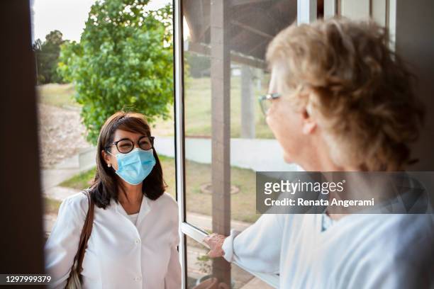 seniorin öffnet die tür für die krankenschwester in der häuslichen gesundheitsversorgung - visit stock-fotos und bilder