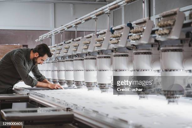 hombre trabajando en máquina de bordar textil - fábrica textil fotografías e imágenes de stock