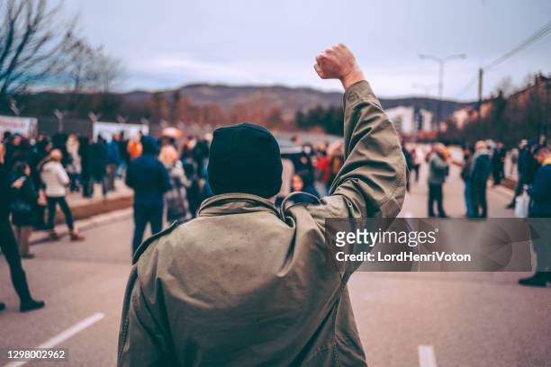 uomo protesta in strada con pugno alzato - dimostrazione di protesta foto e immagini stock