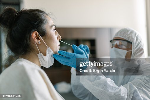 Doctor in protective workwear taking nose swab test from young woman Doctor in protective workwear taking nose swab test from young woman
