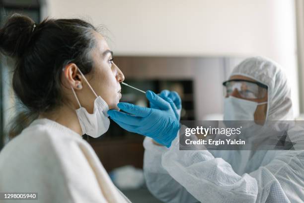 médico em roupa de trabalho protetora fazendo teste de cotonete de nariz de jovem - teste de diagnóstico rápido - fotografias e filmes do acervo