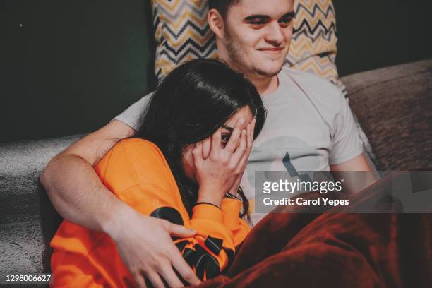 young couple watching a horror movie at home. scared people - couple watching tv photos et images de collection