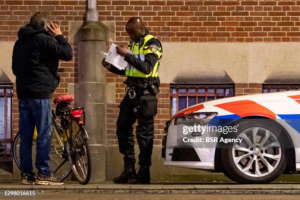Police officer checks papers and reasons to be outside after 9pm on January 23, 2021 in Amsterdam, Netherlands. As of Saturday night a curfew is in...