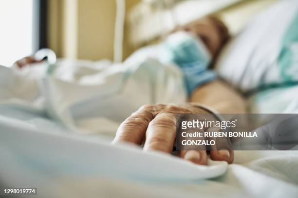 senior woman wearing face mask lying on hospital bed - krankheit stock-fotos und bilder