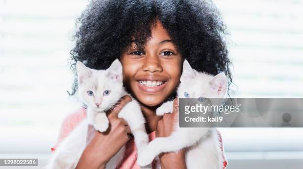 ragazza afro-americana che tiene in braccio due gattini - kid holding cat foto e immagini stock