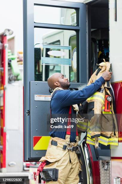 firefighter putting on fire protection suit - firefighter getting dressed stock pictures, royalty-free photos & images