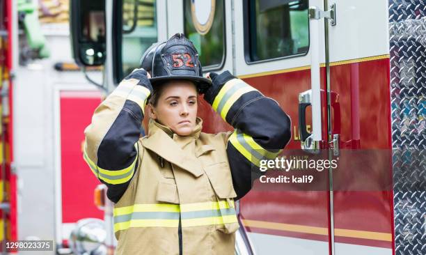 female firefighter putting on helmet - firefighter getting dressed stock pictures, royalty-free photos & images