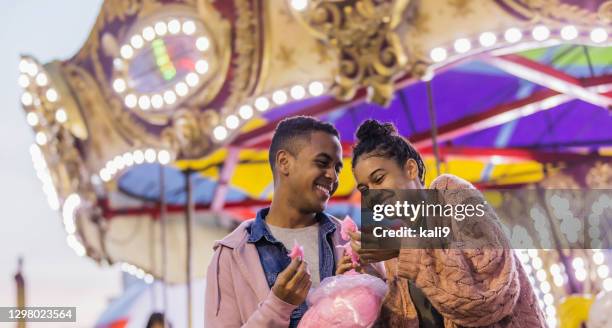 young couple at carnival eating cotton candy - fete stock pictures, royalty-free photos & images