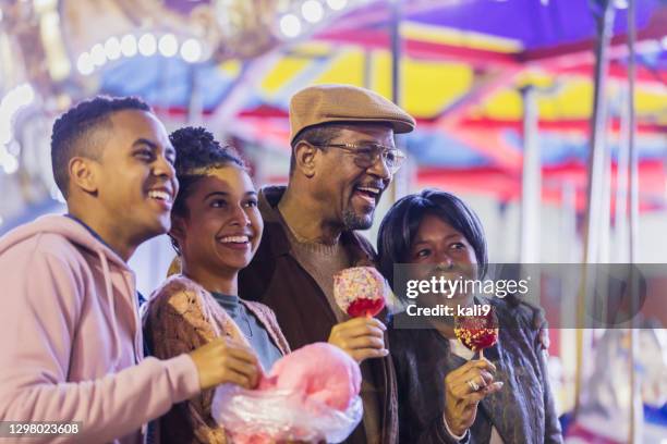 senior couple, adult grandchildren at amusement park - cotton candy stock pictures, royalty-free photos & images