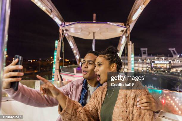 joven pareja afroamericana montando la rueda de la fortuna - noria fotografías e imágenes de stock