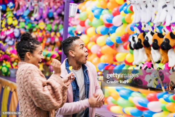 joven pareja afroamericana jugando juego de carnaval - traveling carnival fotografías e imágenes de stock