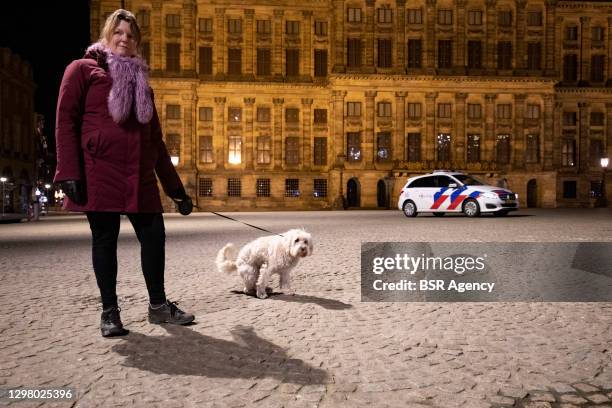 Woman is seen walking her dog on a deserted Dam Square in the city centre on January 23, 2021 in Amsterdam, Netherlands. For the first time in 75...