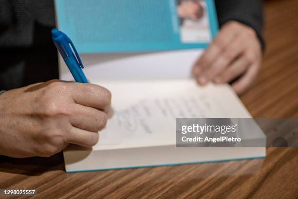 una escritora firma su libro para que sirva de recuerdo a una lectora. - author stock pictures, royalty-free photos & images