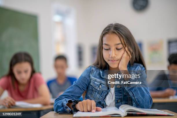 focusing on reading this book - kids in classroom desks stock pictures, royalty-free photos & images