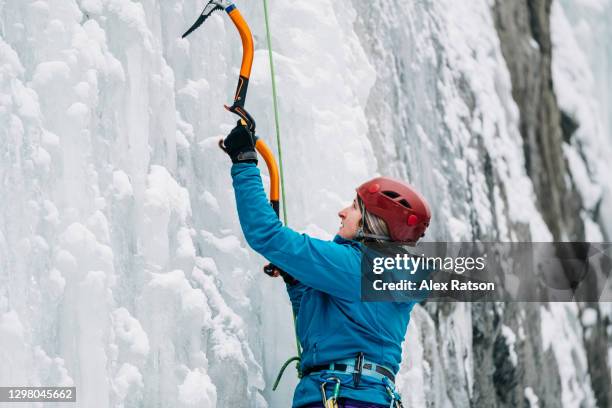 can: close up shot of female ice climber hanging onto ice axe - ice pick stockfoto's en -beelden