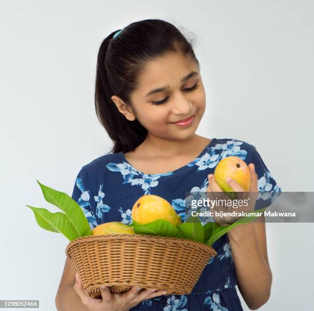leuke gelukkige aziatisch/indisch meisje dat zich met mangomand bevindt - mango juice stockfoto's en -beelden